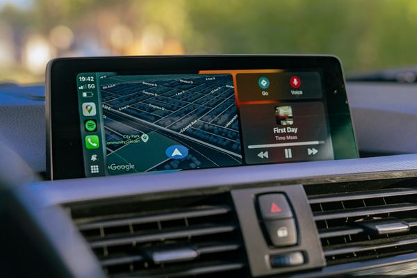 A touchscreen car stereo showing a map and a music player