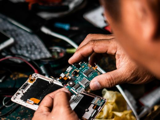 Hands working on a circuit board at a repair bench